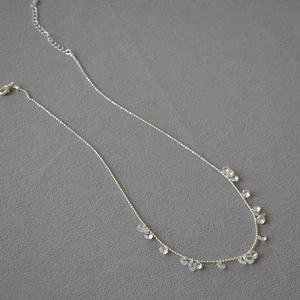 Sparkling silver necklace with teardrop crystal pendants arranged in a crescent shape