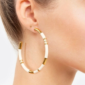 Detailed view of oversized gold plated enamel bamboo hoop earrings with AB engraving