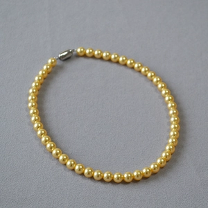 Détail du collier de perles dorées champagne lustrées avec fermoir argenté élégant