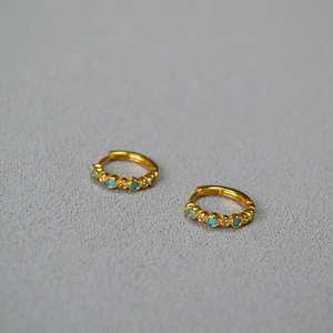 Detail of gold-plated hoop earrings inlaid with turquoise and white zircon stones