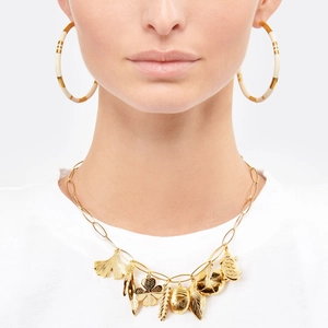 Detail of oversized gold-plated bamboo-style hoop earrings and multi-pendant necklaces