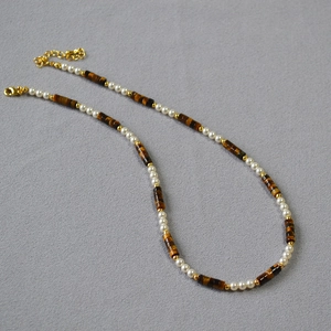 Detail of tiger eye stone and pearl beaded necklace with gold lobster clasp and extension