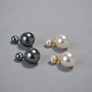 Detail of double-sided faux pearl earrings in white and charcoal gray with gold bases