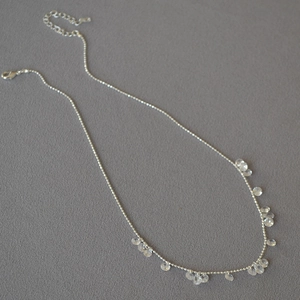 Detailed view of silver bead necklace with transparent teardrop crystal pendants and lobster clasp