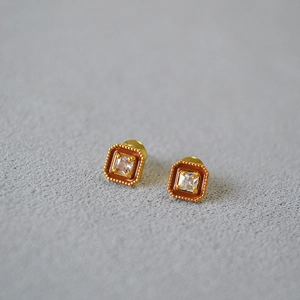 Détail de boucles d'oreilles carrées en émail avec zircone et bordure perlée dorée sur gris