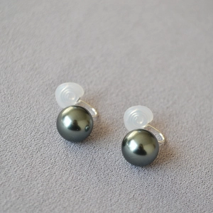 Détail de boucles d'oreilles clips perles gris foncé avec attaches en résine transparente