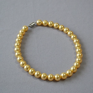 Élégant collier de perles dorées avec fermoir métallique sur fond gris