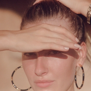 Golden oversized bamboo style hoop earrings with black enamel detail on female model