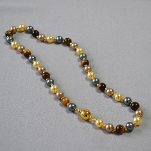 Macro detail of bead necklace with tiger eye stones, pearls and magnetic gold clasp