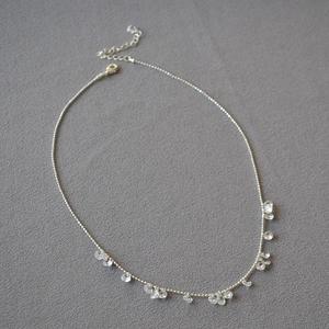 Detail of silver beaded necklace featuring crystal teardrop charms and lobster clasp