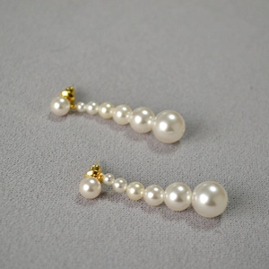 Vue détaillée de boucles d'oreilles pendantes avec perles blanches de tailles graduées