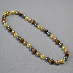Detail view of tiger eye stones, pearls and beads with a gold magnetic sphere clasp