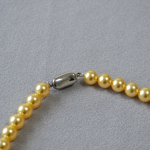 Collier de perles dorées brillantes avec fermoir capsule en métal argenté élégant