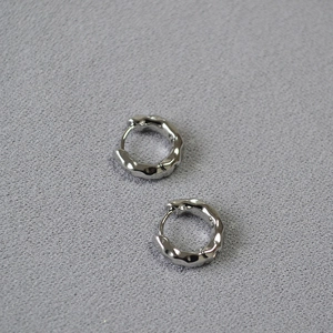 Detail shot of silver hoop earrings with a unique hammered texture and snap closure