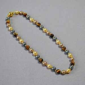 Macro view of beads featuring tiger eye stone and metallic magnetic clasp on jewelry