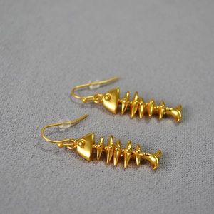 Detailed close-up of vintage gold-plated fishbone earrings with a brushed matte finish