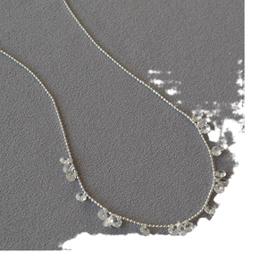 Elegant silver bead necklace featuring sparkling crystal teardrop pendants on grey fabric
