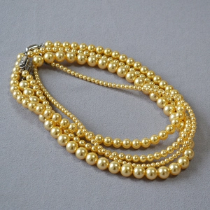 Détail d'un collier de perles dorées à quatre rangs avec fermoir en métal brillant