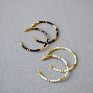 Detail of bamboo joint C-shape hoop earrings with black and cream enamel finish