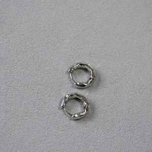 Close-up of silver-plated hammered texture earrings on a grey fabric background