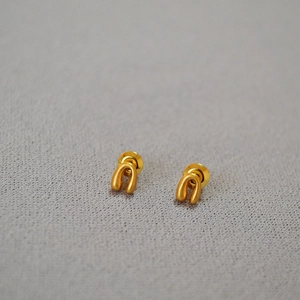 Close-up of gold-plated horseshoe stud earrings with a matte brushed finish on fabric