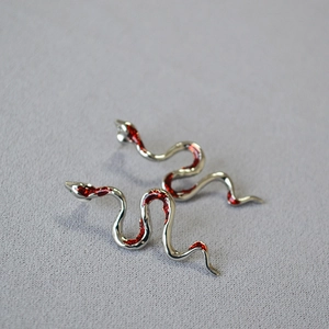 Close-up of silver snake earrings with vibrant red enamel coating in gothic style