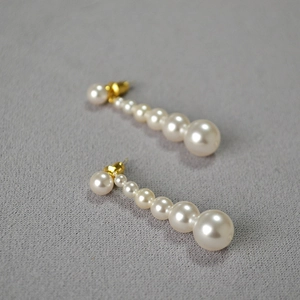 Boucles d'oreilles pendantes avec perles blanches dégradées et tiges dorées sur tissu