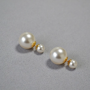 Macro detail of high-luster cream double pearl earrings with golden metallic finish