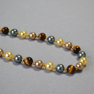Detail of beaded necklace with tiger eye stones, pearls and golden spacers