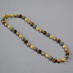 Detail of beaded necklace with tiger eye stones, pearls, and a gold magnetic ball clasp