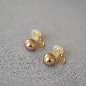 Vue macro de boucles d'oreilles clips perles rondes élégantes avec métal doré en U et silicone