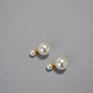 Detail of high-gloss white double pearl earrings with elegant gold metal accents