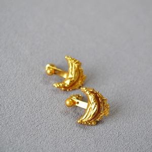 Macro detail of gold-plated crescent earrings with unique lava texture and ball screw backs
