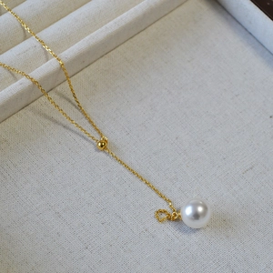 Gros plan d'une chaîne en or avec pendentif perle blanche et boucle coulissante réglable