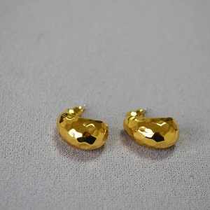 Close-up of vintage golden crescent earrings with hammered texture and retro design