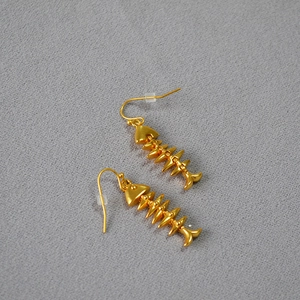 Detailed close-up of vintage gold fishbone drop earrings with a matte texture