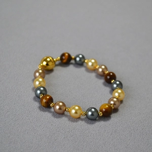Retro tiger eye and pearl beaded necklace with a golden magnetic clasp on grey background