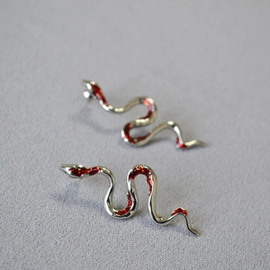 Macro view of silver snake earrings featuring sparkling red glitter enamel finish