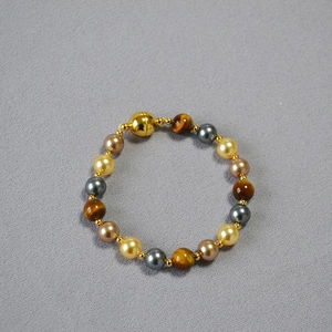 Close-up of tiger eye and colorful pearl beads with a gold spherical magnetic clasp