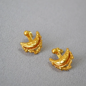 Detail of gold moon-shaped earrings with irregular textured molten lava surface