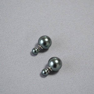 Detail view of double dark grey faux pearl earrings with metallic green luster and silver posts