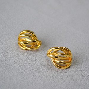 Close-up of golden multi-layered hollow wire woven stud earrings on a grey background