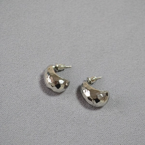 Macro view of vintage hammered silver earrings with textured C-shape design and glossy finish