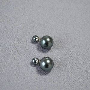 Detailed view of dark grey double pearl earrings with 925 silver needle on grey fabric