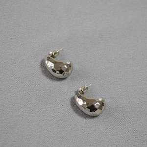 Macro detail of silver stud earrings featuring hammered texture and crescent moon design