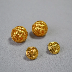 Close-up of vintage gold hollow woven ball stud earrings with intricate wire texture