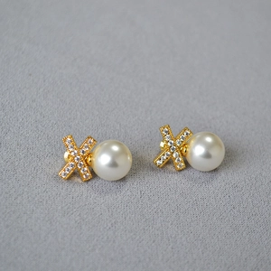 Detail of cross X stud earrings with shimmering zircons and round lustrous pearls