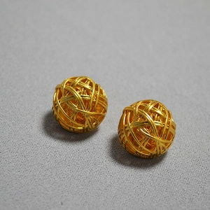 Detailed close-up of gold-plated hollow woven ball earrings with metallic luster