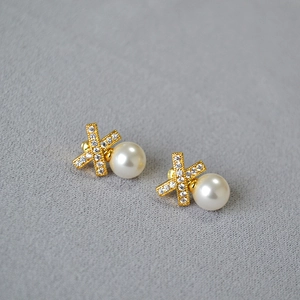 Macro shot of gold X-shaped crisscross pearl earrings with sparkling micro-pave zircons