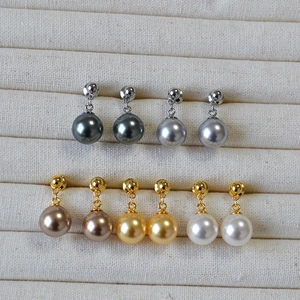 Detail of five pairs of pearl drop earrings in grey, champagne, gold and white hues